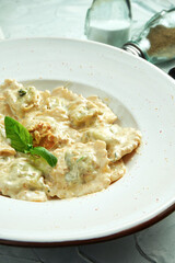 Italian traditional ravioli with minced meat in a creamy nut sauce in a white plate