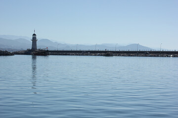Alanya, TURKEY - August 10, 2013: Travel to Turkey. The waves of the Mediterranean Sea. Water surface. Port. Ships on the water. Boats at sea. Yachts and other water transport. Lighthouse. Mountains i