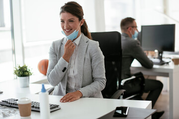 Beautiful businesswoman with medical mask working in office. Young businesswoman working on lap top.	
