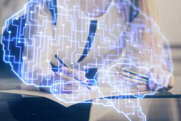 Multi exposure of woman's writing hand on background with brain hud. Concept of learning.