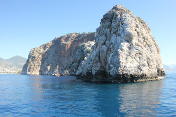 Fototapeta premium Alanya, TURKEY - August 10, 2013: Travel to Turkey. The waves of the Mediterranean Sea. Water surface. Mountains and hills on the coast of Turkey. Port. Green hills.