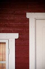 A detail view on a door, window and wood panel painted in red