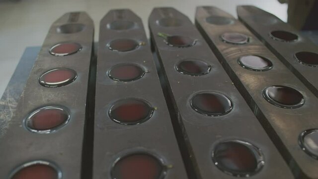 Hot liquid dark colored brown metal or gold in round black vessels that just got out of the induction furnace at modern industrial line of precious metal production factory, close up, slow motion, 4k 