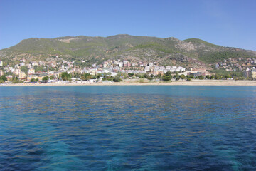 Alanya, TURKEY - August 10, 2013: Travel to Turkey. The waves of the Mediterranean Sea. Water surface. Mountains and hills on the coast of Turkey. Green hills. Port.