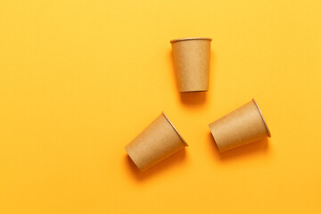 Paper cups in a chaotic position on an orange background with space for text. Minimal flat lay