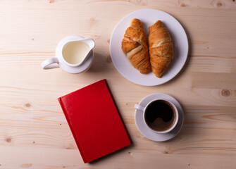 a white ceramic cup with black espresso, french croissant as breakfast or snack concept on rustic, natural texture wooden surface