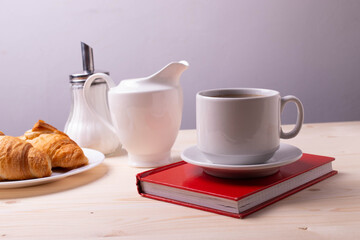 a white ceramic cup with black espresso, french croissant as breakfast or snack concept on rustic, natural texture wooden surface