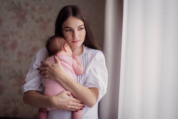 A young mother rocks her kid and sings a lullaby at home. A restless Child does not sleep. Caring...