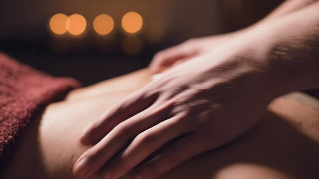 close-up Cosmetology and physiotherapy. Professional massage to the lower back of a woman is made by a masseur man. Concept of manul therapy and massage spa treatments