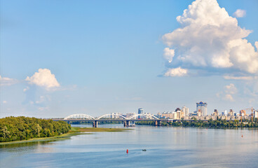 Fototapeta premium A large figured cloud hung over the city near the railway bridge near the Dniprо River.