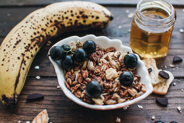 Healthy breakfast ingredients. Homemade granola, oatmeal, yogurt in the bottle, honey, berries and fruits on a wooden background. Morning aesthetics and beautiful layout on a wooden table.