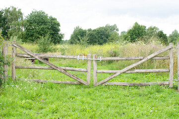 Fototapeta na wymiar Old wooden closed gate that gives access to a meadow