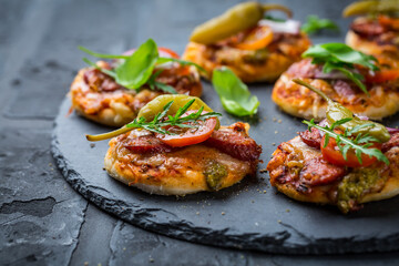 Homemade small pizza with pesto, salami, tomatoes and arugula