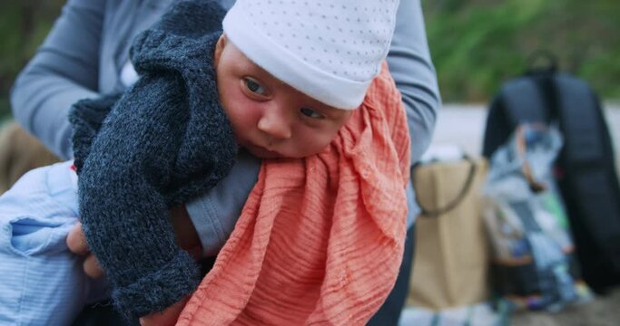 Grandmother on beach comforting baby grandchild and burping him