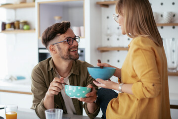 Happy couple eating breakfast at home. Husband and wife enjoying in the morning.	