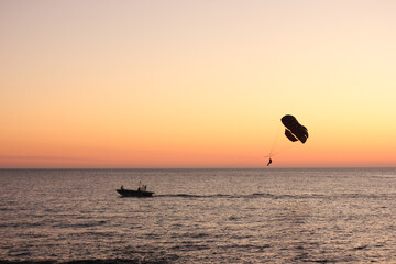 Parasailing. Active type of recreation at the sea. Parachute flights behind a boat at sunset.