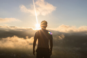 Obraz premium Young man looking beautiful view of foggy mountains landscape