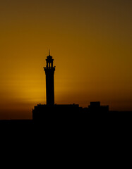 Sunset in the desert with a mosque in the forground asa silhouette on the Arabian peninsula 