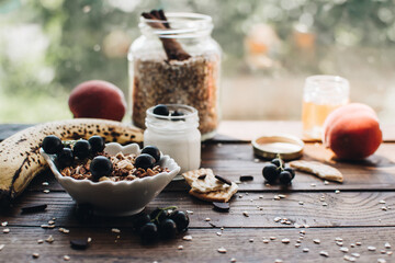 Healthy breakfast ingredients. Homemade granola, oatmeal, yogurt in the bottle, honey, berries and fruits on a wooden background. Morning aesthetics and beautiful layout on a wooden table.