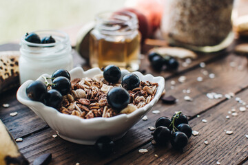 Healthy breakfast ingredients. Homemade granola, oatmeal, yogurt in the bottle, honey, berries and fruits on a wooden background. Morning aesthetics and beautiful layout on a wooden table.