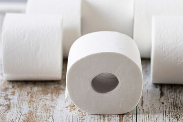 A pile of soft toilet paper rolls on a wooden background