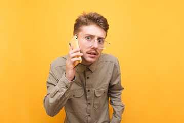 Funny nerd with mustache and glasses talking on the phone and looking into the camera with a...