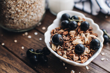 Healthy breakfast ingredients. Homemade granola, oatmeal, yogurt in the bottle, honey, berries and fruits on a wooden background. Morning aesthetics and beautiful layout on a wooden table.