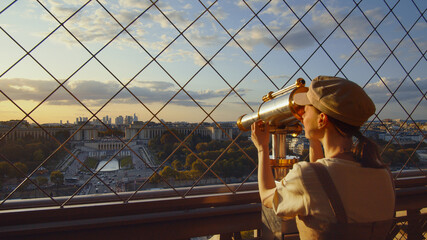 Young tourist looking through binoculars at the view point