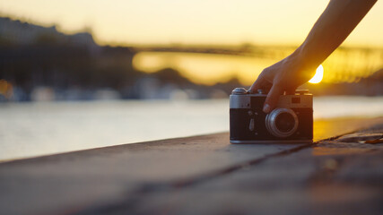 Young photographer with a retro camera at sunset