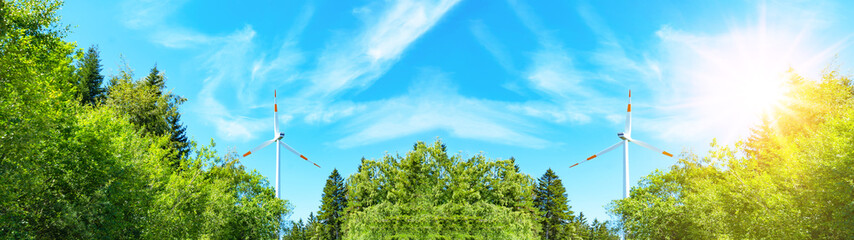 Wind power background banner wide panoramic panorama - Blue cloudy sky with many windmill / wind turbines, sunshine and green trees in the forest in Germany ( Black Forest )