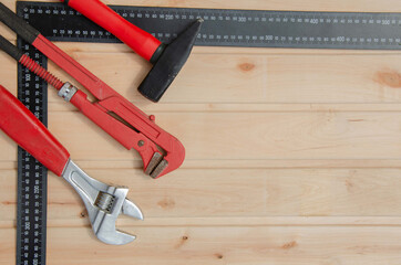 Red tools for repair. Hammer metal wrenches. Tools angle ruler wooden background.