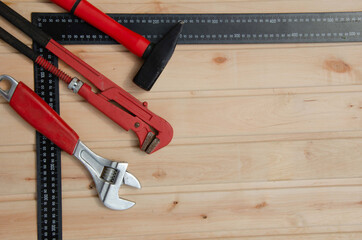Red tools for repair. Hammer metal wrenches. Tools angle ruler wooden background.