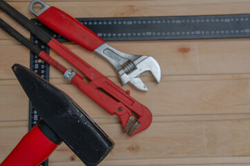 Red tools for repair. Hammer metal wrenches. Tools angle ruler wooden background.