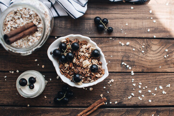 Healthy breakfast ingredients. Homemade granola, oatmeal, yogurt in the bottle, honey, berries and fruits on a wooden background. Morning aesthetics and beautiful layout on a wooden table.