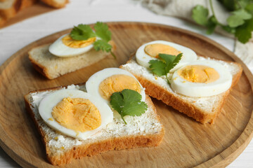 Tasty sandwiches with boiled eggs on wooden tray, closeup
