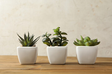 Artificial plants in white flower pots on wooden table