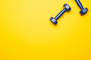 Fototapeta na wymiar top view of blue dumbbells on yellow background