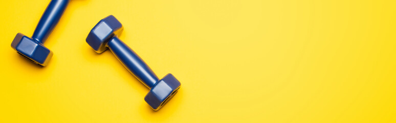 top view of blue dumbbells on yellow background, panoramic shot