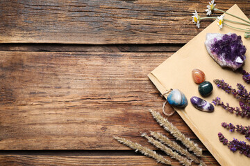 Flat lay composition with different gemstones and healing herbs on wooden table, space for text
