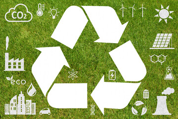 White recycling symbol on green grass background with ecology icons