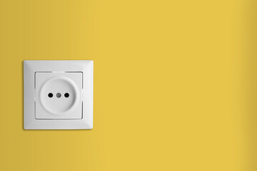 Yellow wall with power socket, space for text. Electrical supply