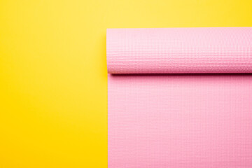 top view of pink fitness mat on yellow background