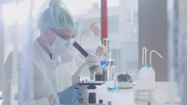 A female scientist researching a blood sample with a microscope in the modern lab.
