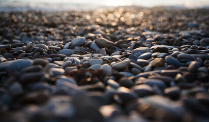 Beautiful multicolored stones on the pebbly beach of the Mediterranean sea at sunset
