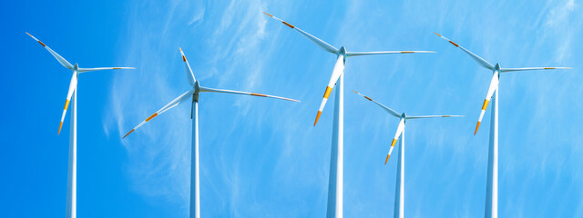 Wind power background banner wide panoramic panorama - Blue cloudy sky with many windmill / wind...