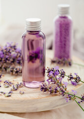 Obraz na płótnie Canvas Lavender bath cosmetics products in bottles on white wooden rustic board, fresh lavender flowers, candle, soap, bath beads, Lavender essential oil, natural spa products. Aromatherapy treatment