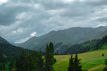 Green mountain valley with clouds. Adventure travel. Outdoor landscape. Summer vacation travel concept. Kazakhstan mountains, Tekes river valley. Tourism in Kazakhstan concept.