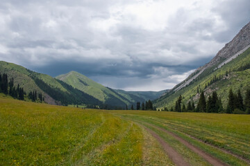 Green mountain valley with clouds. Adventure travel. Outdoor landscape. Summer vacation travel concept. Kazakhstan mountains, Tekes river valley. Tourism in Kazakhstan concept.