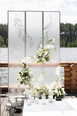 Close up of wedding ceremony with white transparent screens and fresh white flowers and candles