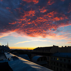 Fototapeta na wymiar Roofs of Saint-Petersburg, Russia. Cityscape panorama of city on sunset, view from a roof. Blazing sky, dramatic sunset. Sky is like a conflagration, majestic atmosphere